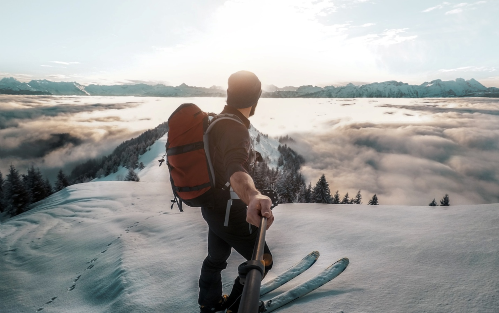 A man using a selfie stick to capture the snow-covered landscape